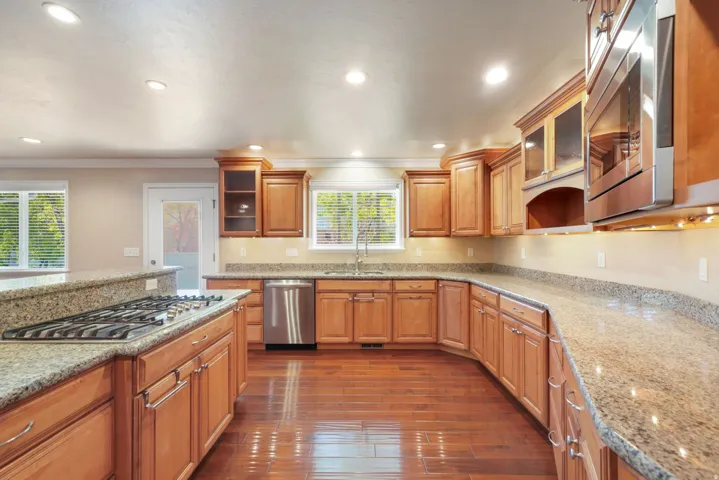 Kitchen featuring wood-finish flooring, recessed lighting, wood cabinetry, granite countertops, and stainless steel appliances