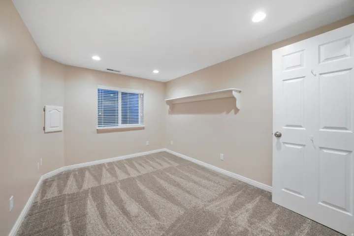 Recessed lighting, window with blinds, decorative wall shelf, paneled interior door, and patterned carpet