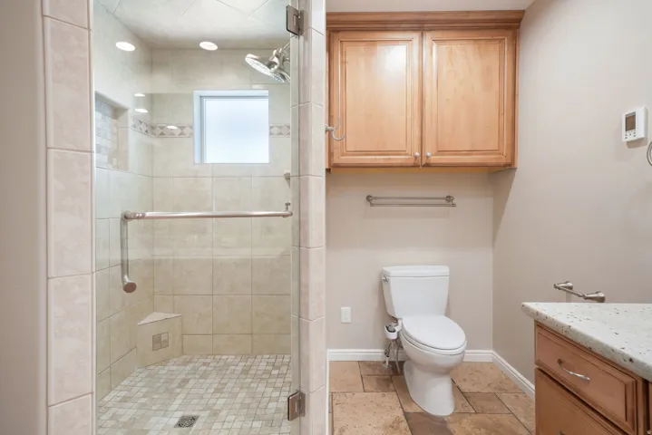 Glass-enclosed shower with tile surround and mosaic floor, built-in shower bench, and recessed lighting