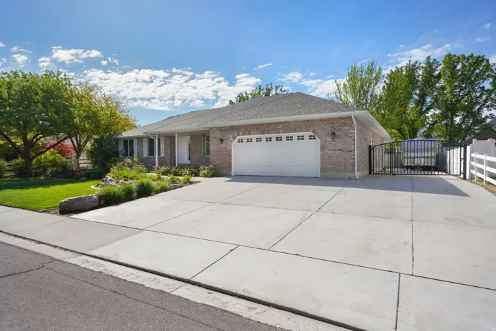 Brick exterior with a two-car garage, concrete driveway, and side access gate