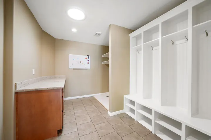 Built-in white storage lockers, skylight, recessed lighting, wood-finish cabinetry, and solid surface countertop