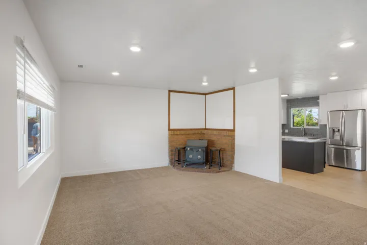 Recessed lighting, brick hearth, wood-finish flooring, white cabinetry, and stainless steel appliances