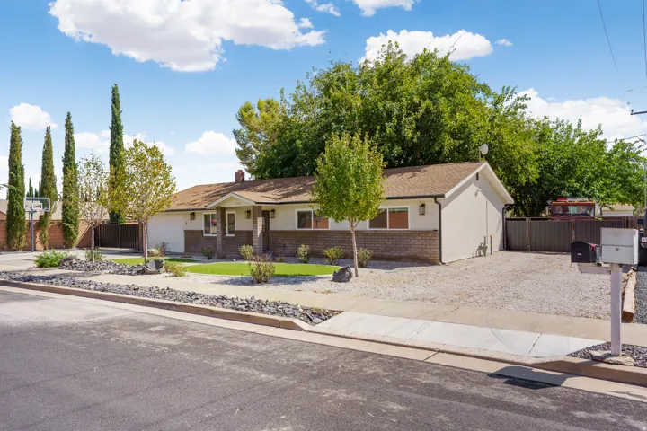 Single-story residence featuring a combination of stucco and brick siding, a brown shingle roof, and a gravel driveway