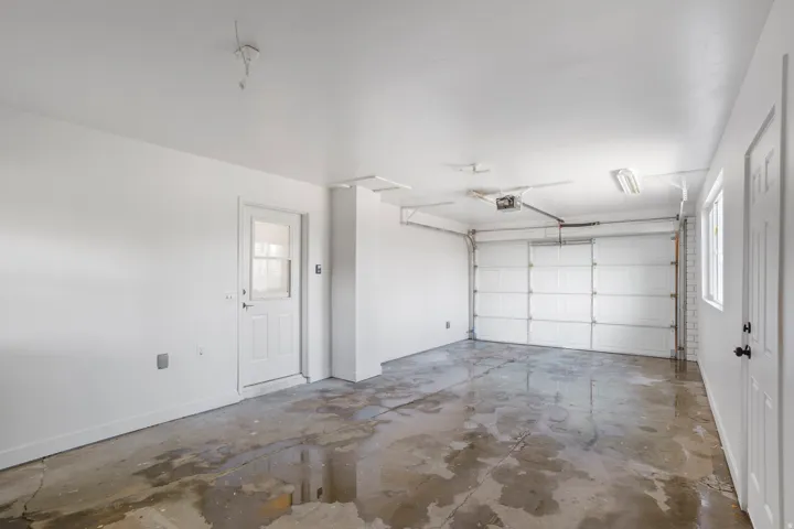 Attached garage with concrete flooring, overhead fluorescent lighting, and a white paneled garage door
