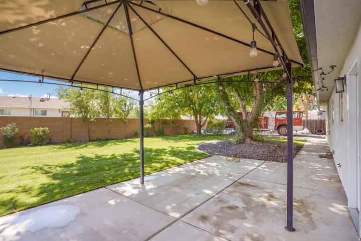 Concrete patio with a freestanding canopy, string lighting, and direct access to a grassy yard