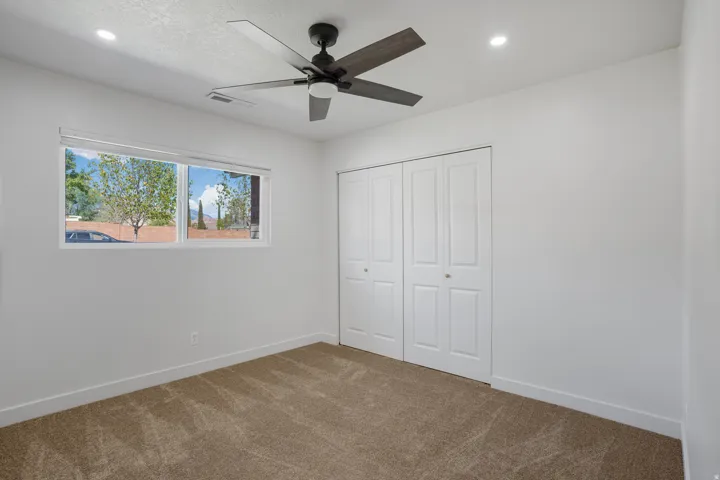 Recessed lighting with a ceiling fan, dual bi-fold closet doors, and light-colored carpeting