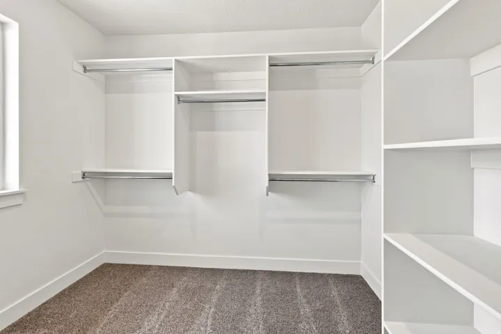 Built-in closet system featuring multiple hanging rods, integrated shelving units, and carpet flooring