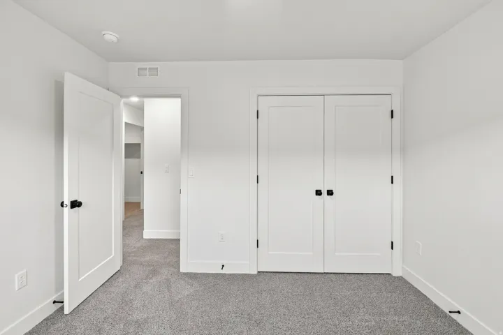 White walls, light gray carpet, white flat-panel interior doors, black door hardware, and recessed lighting