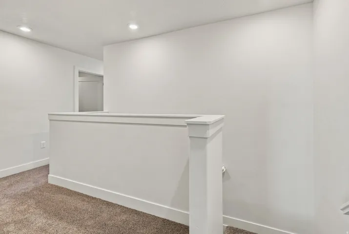 Recessed ceiling lighting, textured wall finish, and carpeted flooring