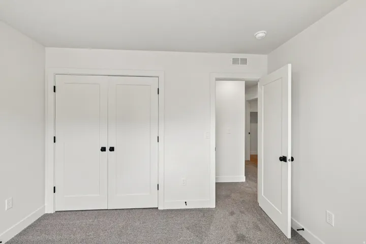 White paneled doors with matte black hardware, grey carpet flooring, and white painted walls