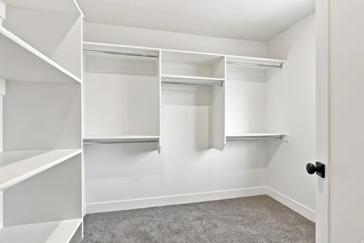 Built-in closet system with shelving, multiple hanging rods, and grey carpeting