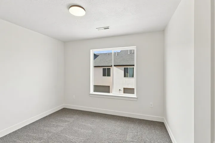 Neutral wall paint, textured ceiling, flush-mount ceiling light, single window, and carpet flooring
