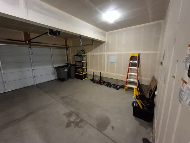 Attached garage with a sectional overhead door, concrete flooring, and overhead lighting