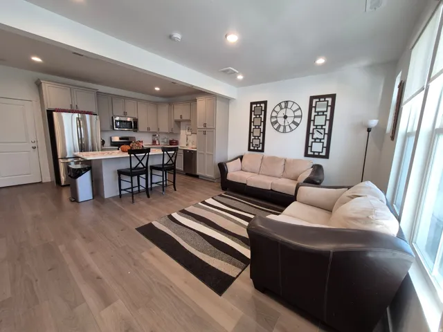 Open-concept living area with wood-finish flooring, recessed lighting, and large windows