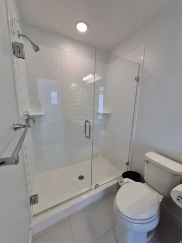 Shower with glass enclosure, subway tile surround, recessed lighting, and integrated shelving