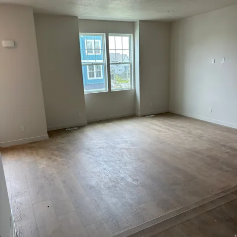 Light wood-finish flooring, white walls, double window, and recessed lighting