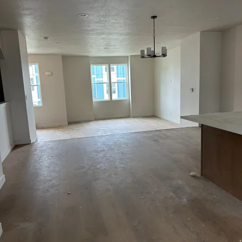 Spacious open-concept living area with wood-finish flooring, recessed lighting, and a contemporary chandelier