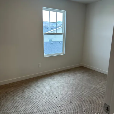 Carpeted room with a single pane window, white walls, and a white trim