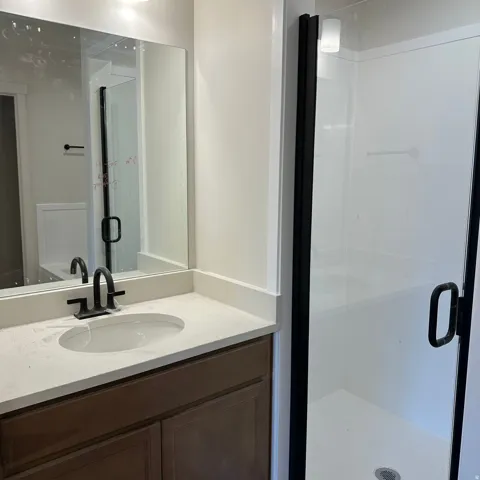 Built-in vanity with wood-finish cabinetry, light-toned countertop, and undermount sink