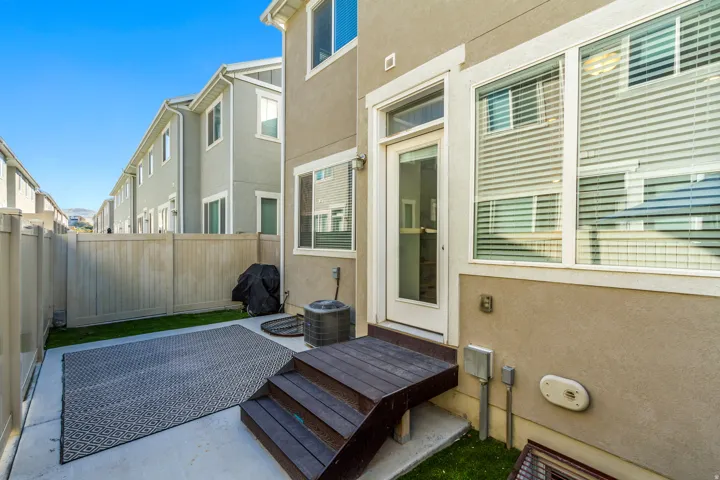 Private fenced yard with concrete patio, artificial turf, and wood-finish steps