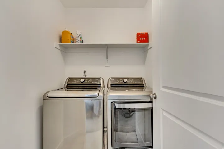 Laundry area with a front-loading washer and dryer set, featuring an overhead storage shelf