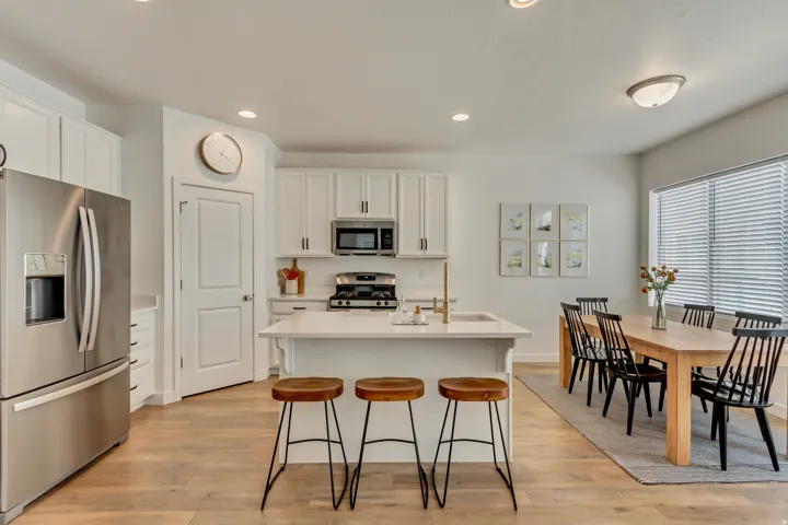 Stainless steel appliances, white cabinetry, recessed lighting, wood-finish flooring, and a kitchen island with seating