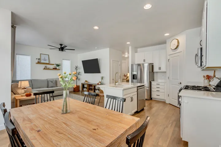 Open-concept living space featuring a spacious kitchen island, stainless steel appliances, recessed lighting, wood-finish flooring, and a ceiling fan