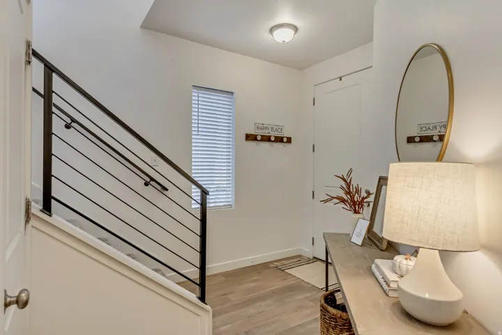 Modern black metal stair railing, wood-finish flooring, white walls, and a window with blinds