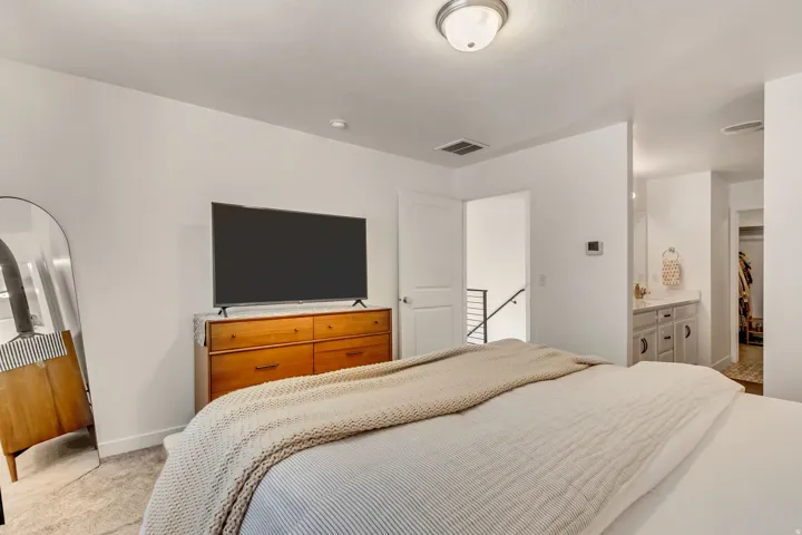 Recessed ceiling lighting, light-toned wall paint, neutral-toned carpeting, and a built-in vanity with cabinetry