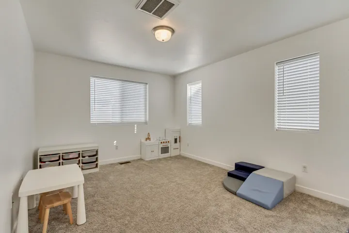 Carpeted room featuring multiple windows with blinds, a flush mount ceiling light fixture, and light-toned wall finishes