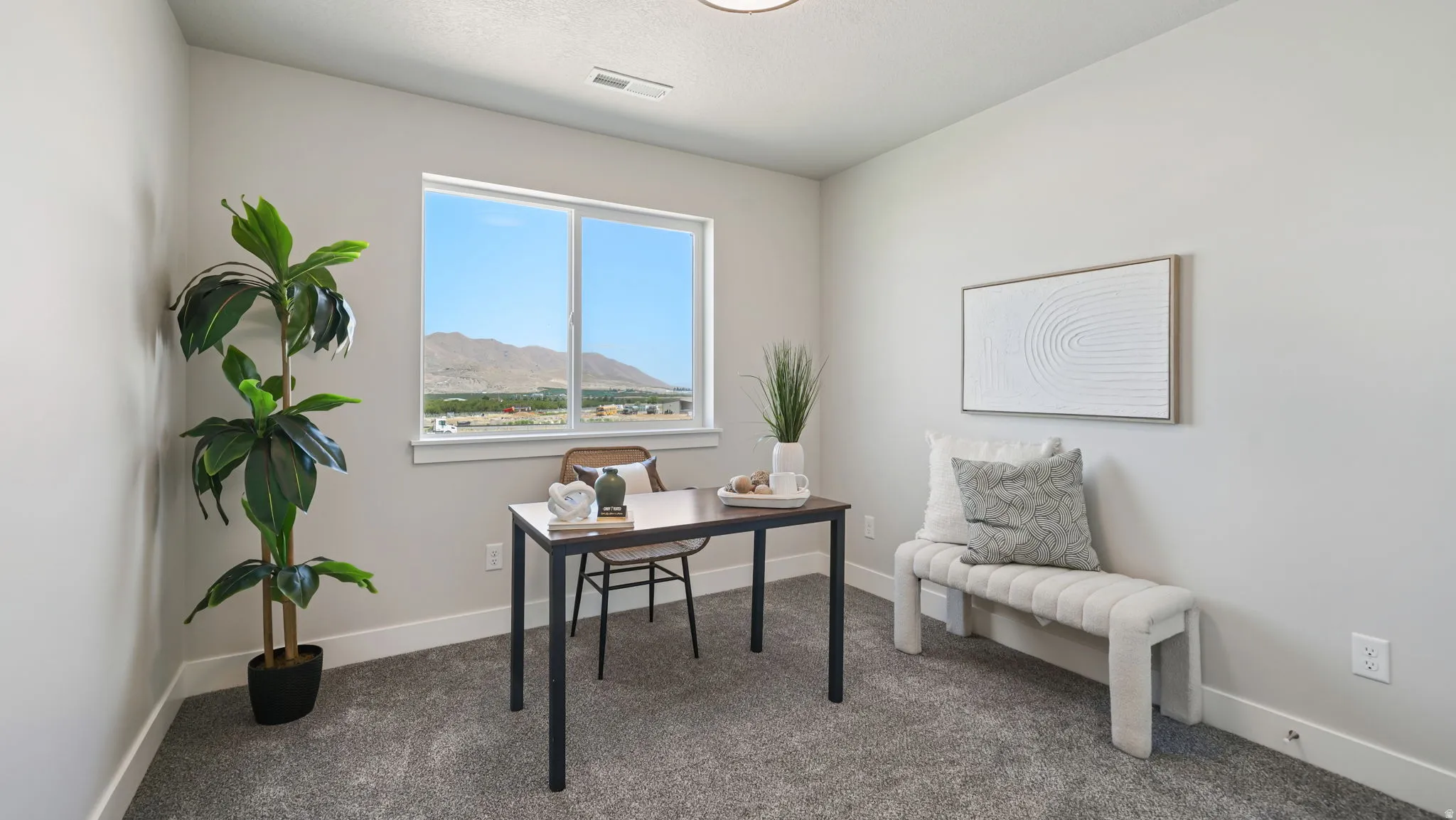 Recessed lighting, large window, mountain scenery, light gray walls, and gray carpet flooring