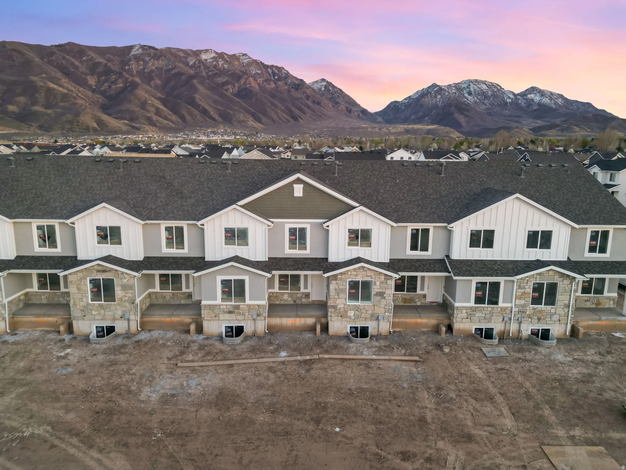 Multi-level townhome exteriors featuring stone accents, gabled roofs, and an array of windows