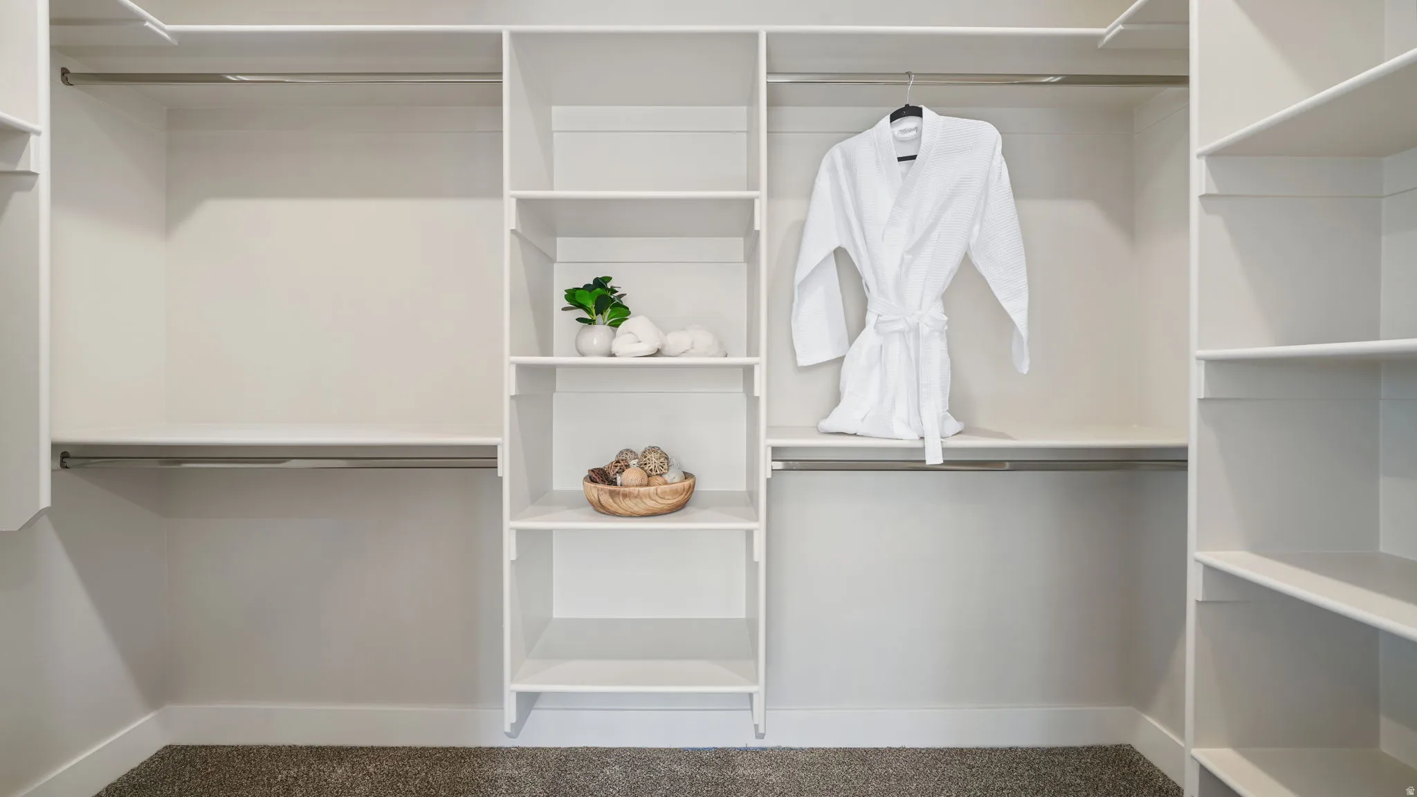 Integrated closet system with multiple shelving units, hanging rods, and light-toned walls