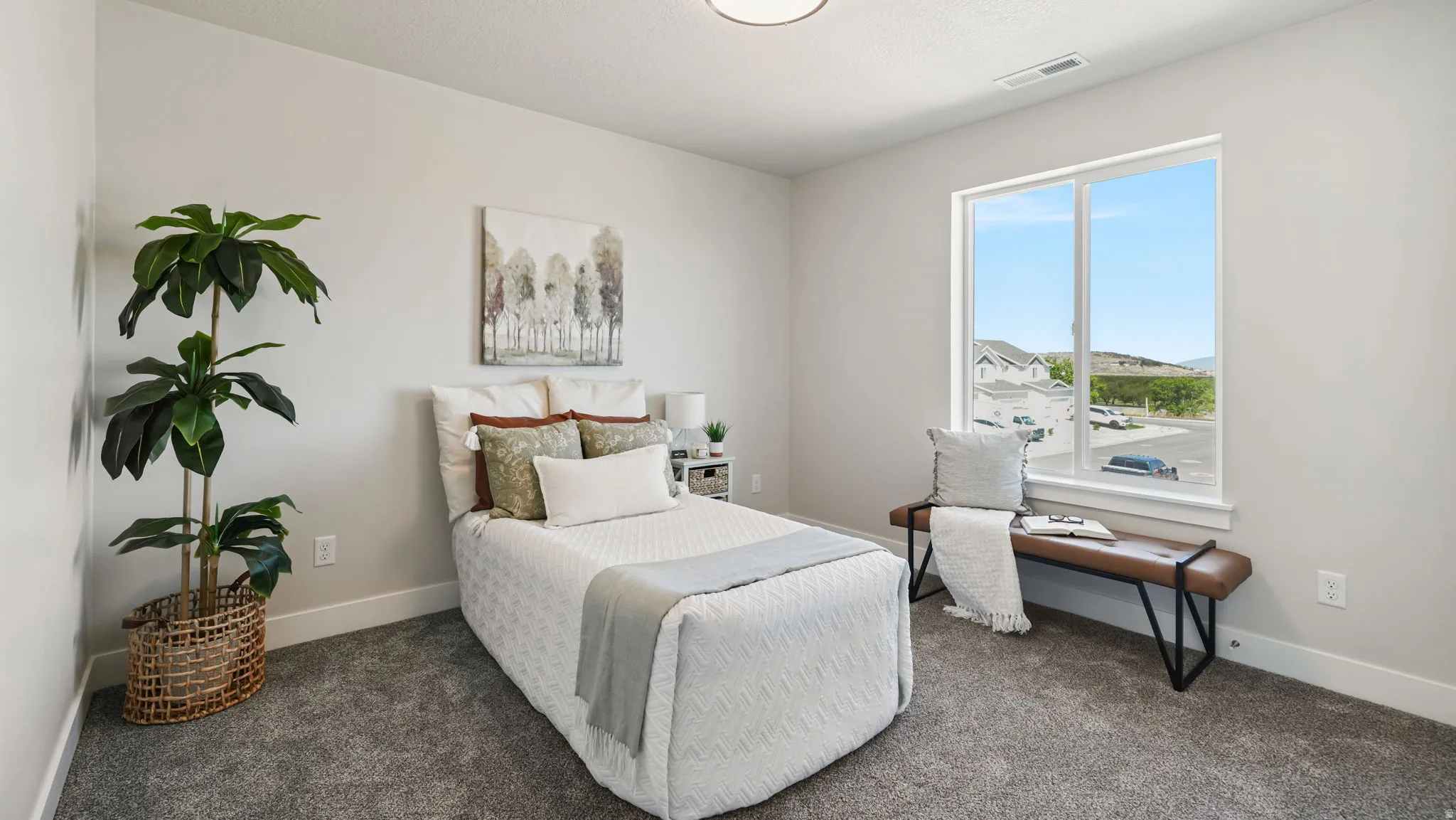 Neutral wall paint, gray carpeting, and a large window with white trim