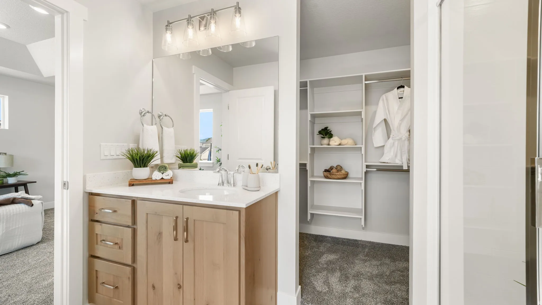 Vanity with a single basin sink, a large mirrored wall, and a four-light fixture
