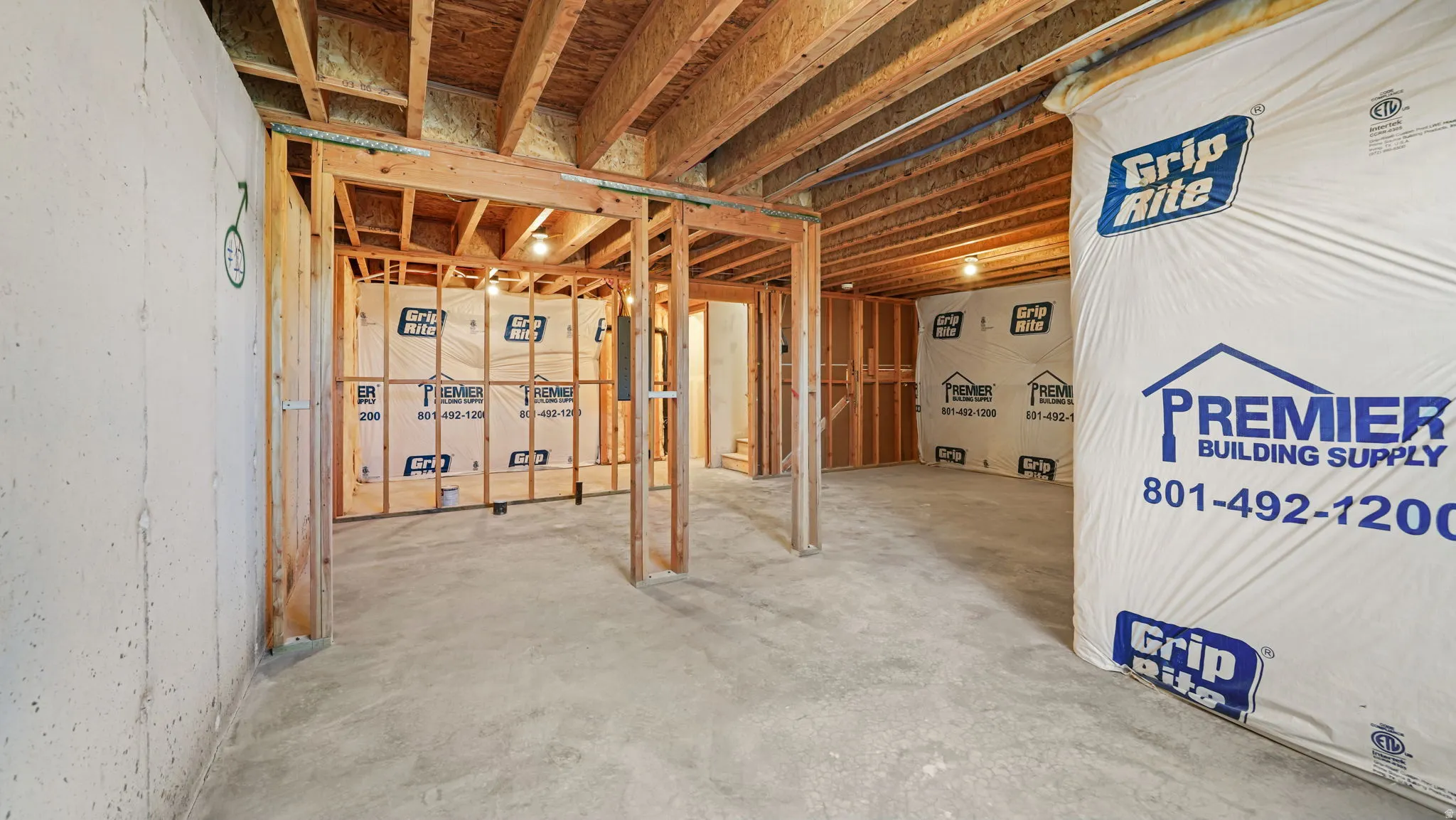 Unfinished basement with exposed wood framing, concrete flooring, and visible ceiling joists