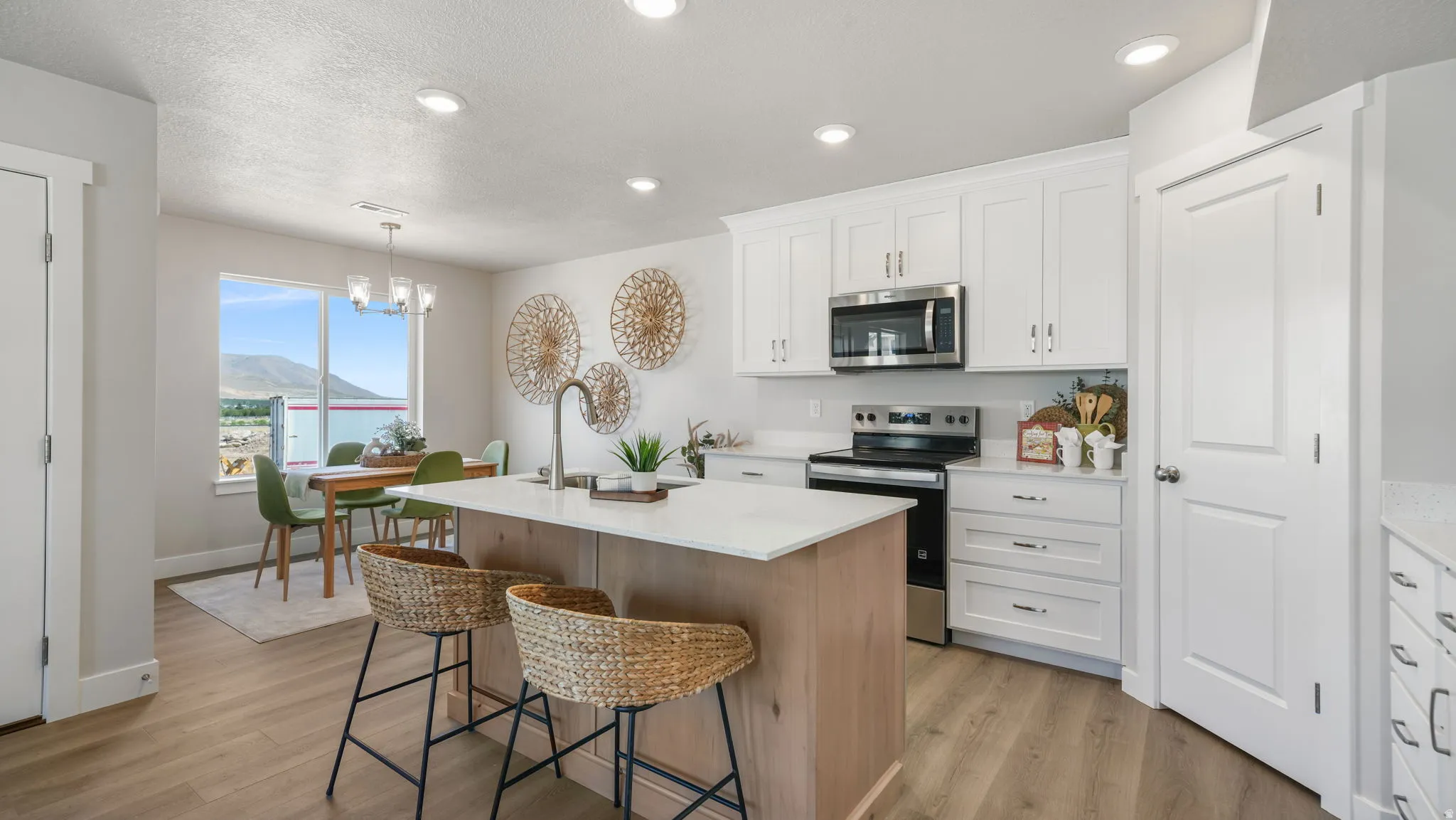 Kitchen featuring a center island with countertop seating, white shaker cabinetry, stainless steel appliances, and wood-finish flooring