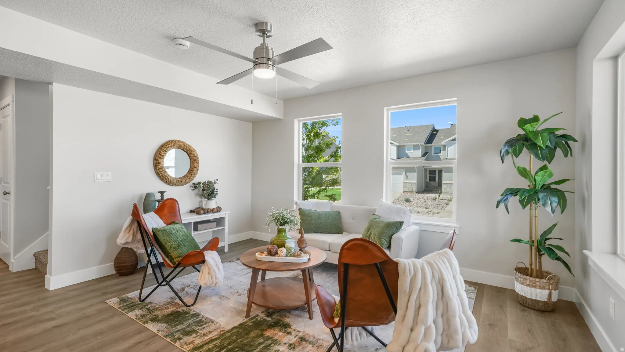 Living area featuring multiple windows, wood-finish flooring, a ceiling fan with integrated lighting, and white trim