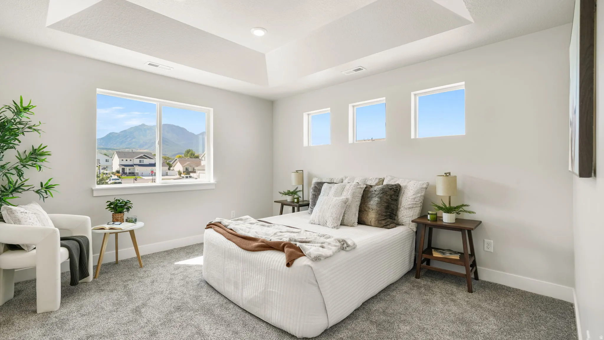 Tray ceiling, recessed lighting, wall-to-wall carpeting, multiple windows, and a mountain backdrop