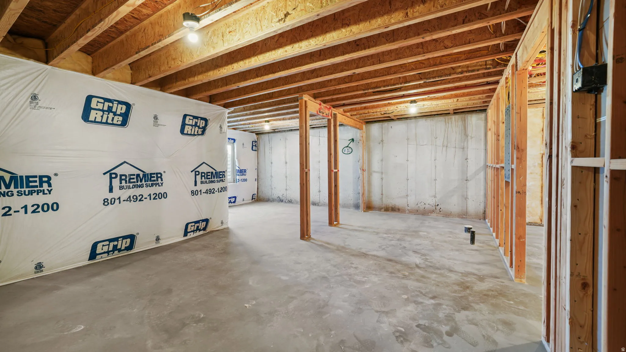 Unfinished basement with exposed wood joists and concrete flooring