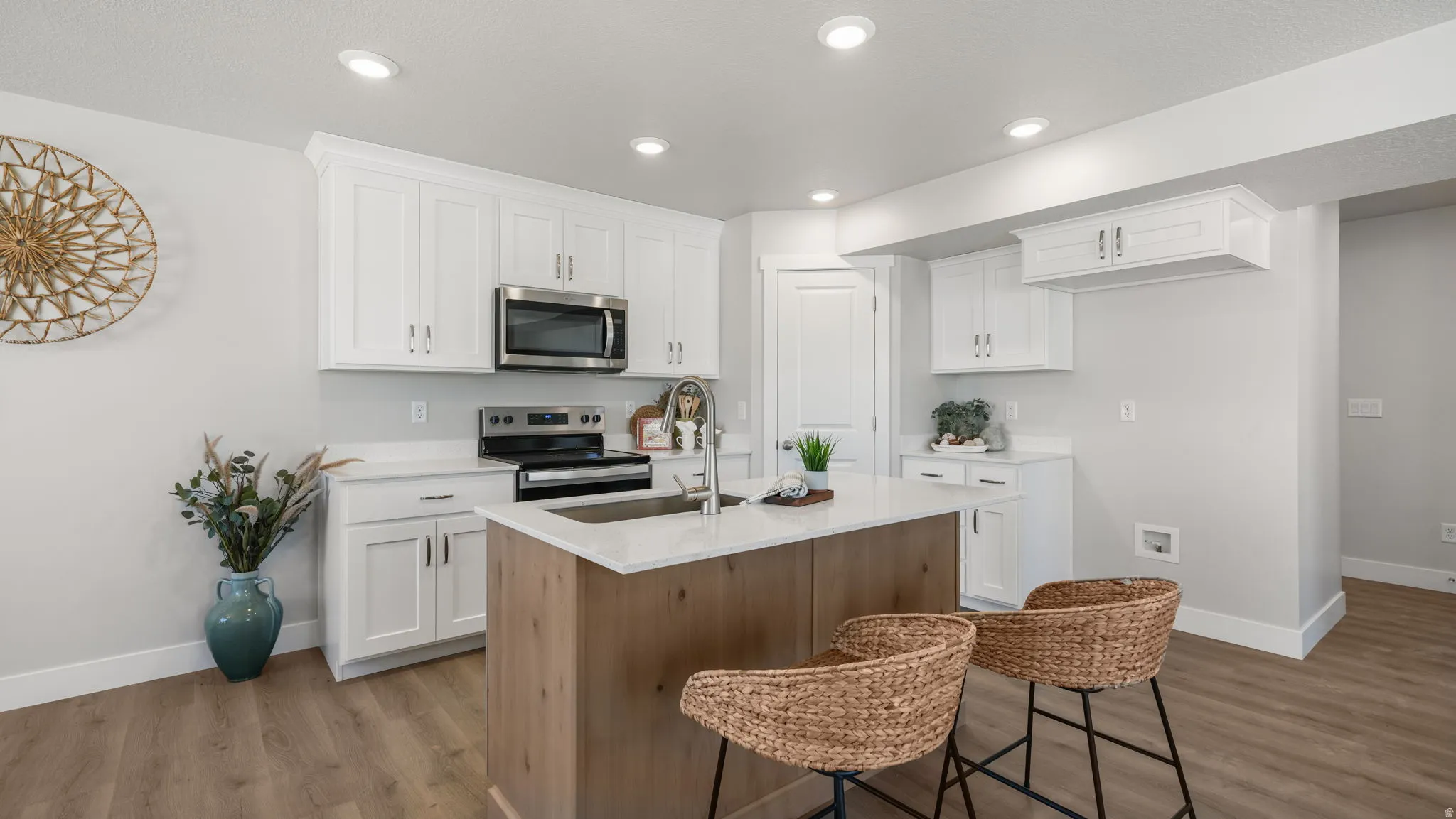 Kitchen featuring white cabinetry, stainless steel appliances, a wood-finish island with a sink, and recessed lighting