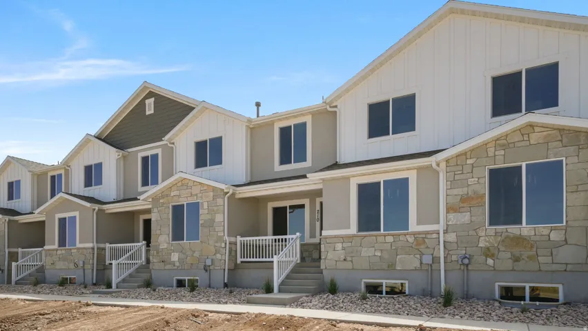 Contemporary townhome exterior featuring stone accents, board and batten siding, and a gabled roofline