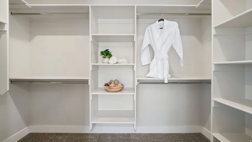Integrated closet system with multiple shelving units, hanging rods, and light-toned walls