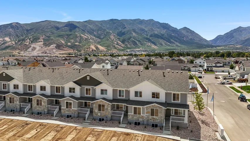 Modern townhome community featuring varied facade finishes, multiple roof lines, and mountain scenery