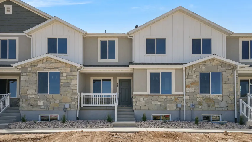 Stone and siding exterior with a covered entry, white porch railings, and a prominent front door
