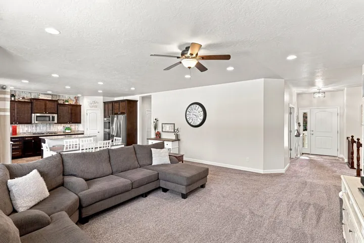 Open-concept living area with recessed lighting, ceiling fan, and carpet flooring