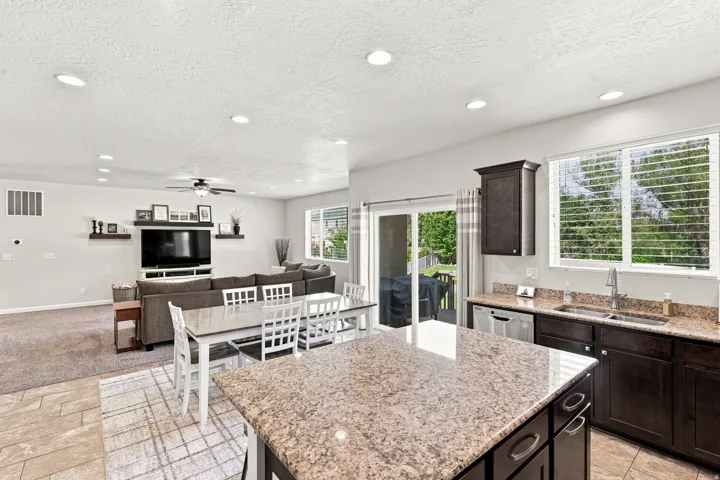 Open-concept living area with recessed lighting, dark wood-finish cabinetry, and light-toned countertops