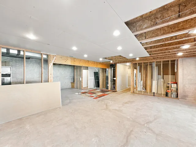 Unfinished basement with exposed wood framing, concrete flooring, and recessed ceiling lighting