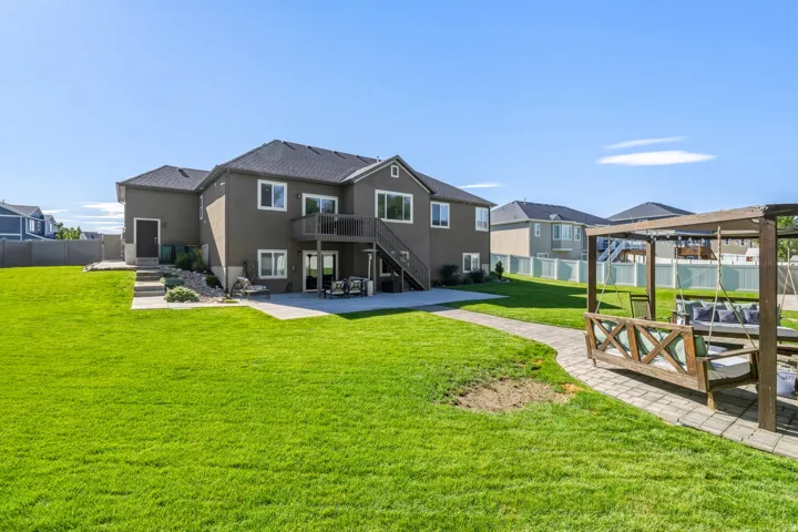 Expansive backyard featuring a manicured lawn, concrete patio, and paver stone walkway