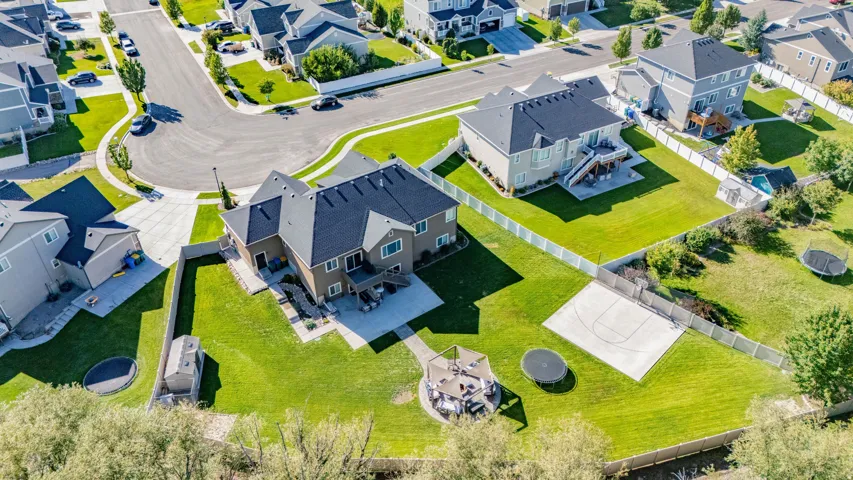 Expansive backyard featuring a concrete patio, a detached storage shed, a full-size sports court, and mature landscaping